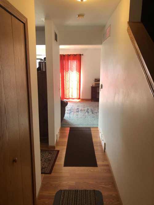 A hallway with a red curtain in the background and a black mat on the floor.
