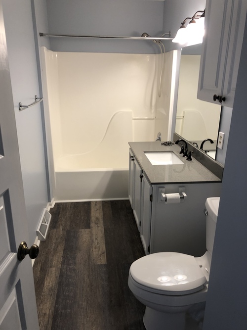 A white toilet is in a small bathroom with a sink and mirror.