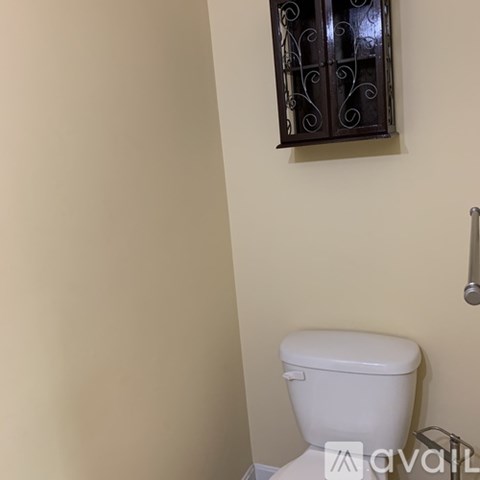 A white toilet in a bathroom with a cabinet above it.