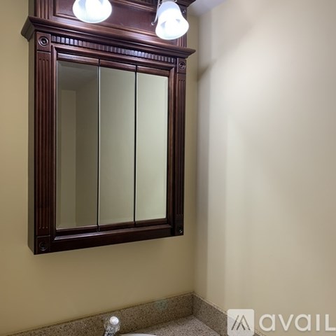 A brown medicine cabinet with a mirror above a sink.