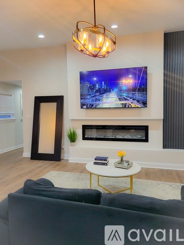 A living room with a grey sofa and a television mounted on the wall.