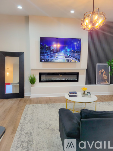 A living room with a grey couch and a television mounted above a fireplace.