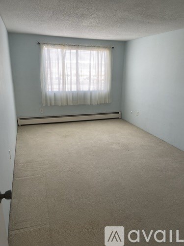 A room with a window covered by a white curtain.