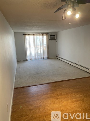 A room with a ceiling fan and a window with curtains.