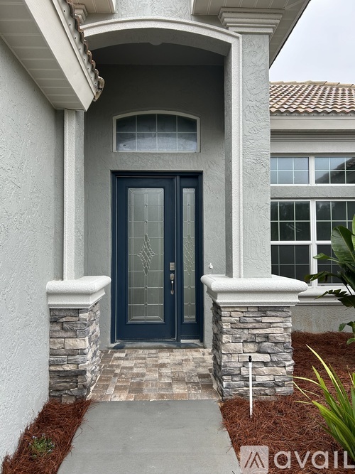 A house with a dark blue front door and a stone pillar.