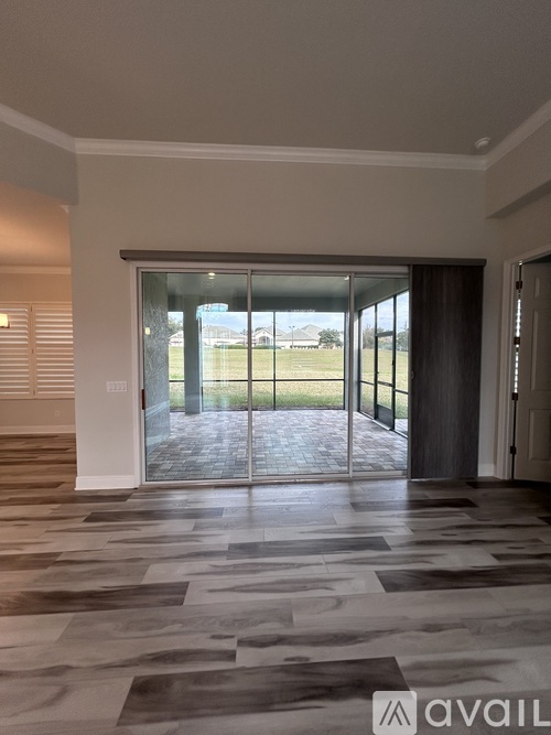 A room with a tiled floor and a sliding glass door leading to a grassy area.