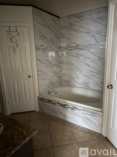A bathroom with a marble tile wall and a bathtub.