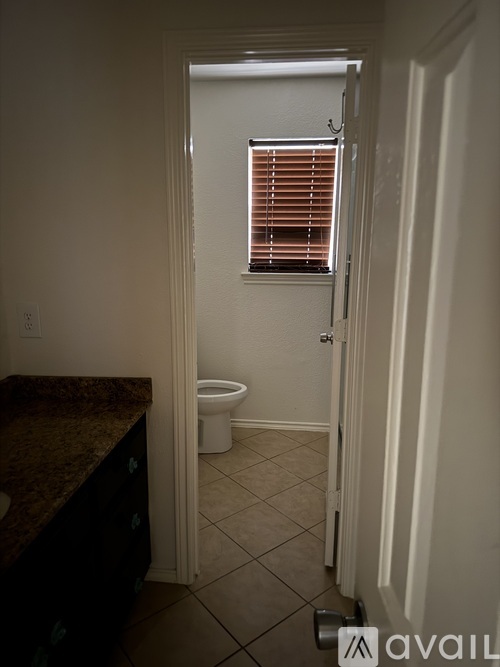 A bathroom with a toilet and a window with blinds.