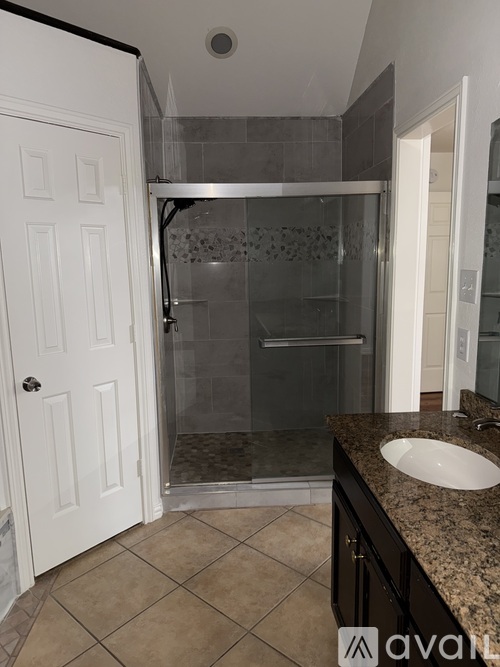 A bathroom with a sink, mirror, and shower.