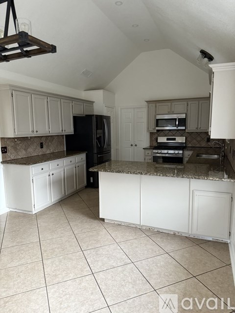 A kitchen with white cabinets and a black refrigerator.