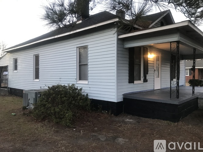 A small white house with a black roof and a porch.