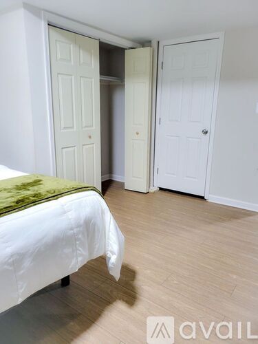 A bedroom with a bed, a green pillow, and two doors.