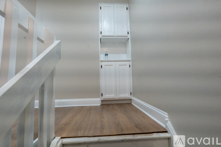 A white cabinet with a door is in the corner of a room.
