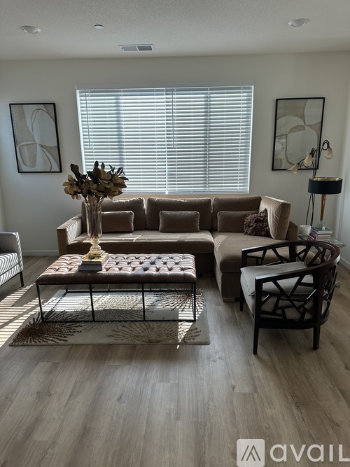 A living room with a brown sofa, a coffee table, and a large window with blinds.