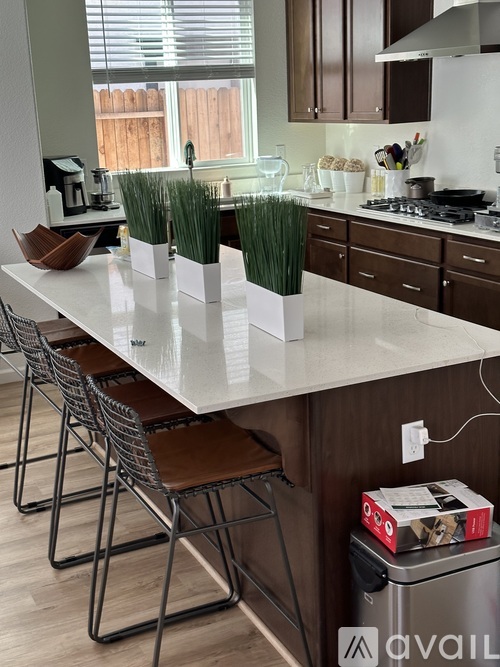 A kitchen with a white countertop and brown chairs.