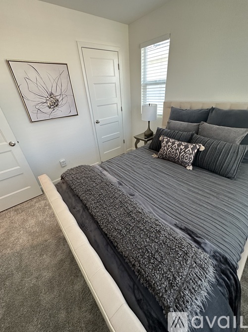 A bedroom with a large bed and a framed picture on the wall.