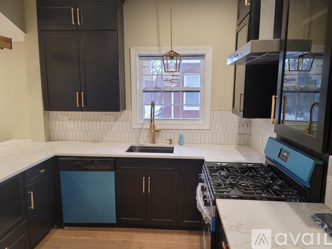 A kitchen with black cabinets and a blue dishwasher.