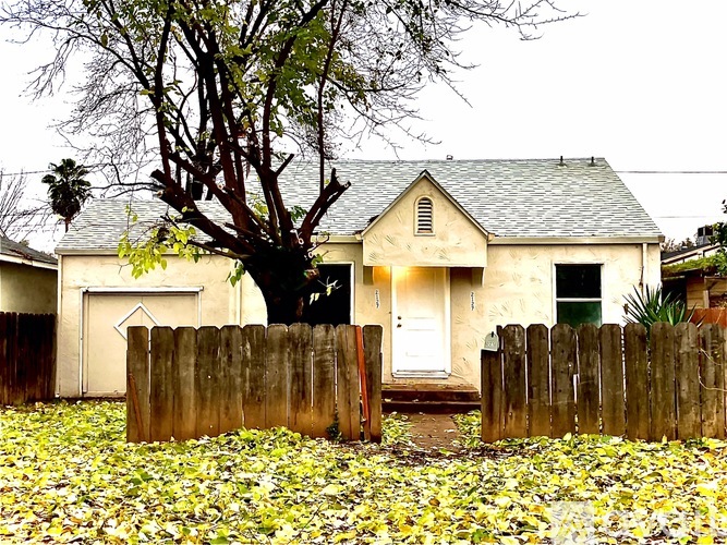 A house with a white door and a tree in front.
