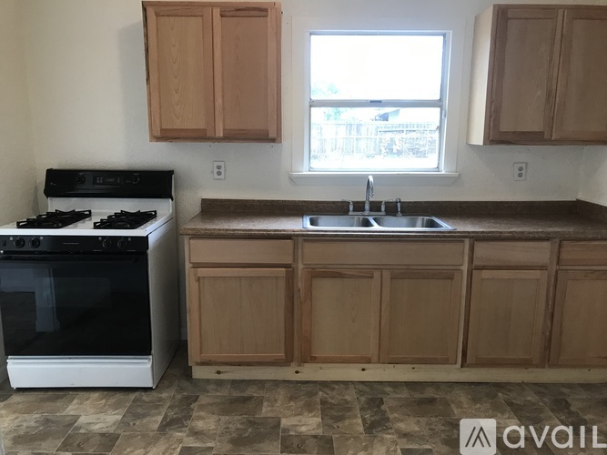 A kitchen with a black stove and wooden cabinets.