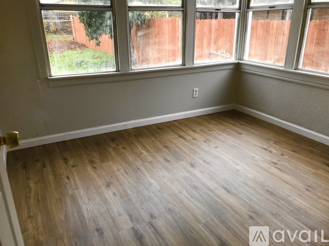 A room with wooden flooring and large windows.