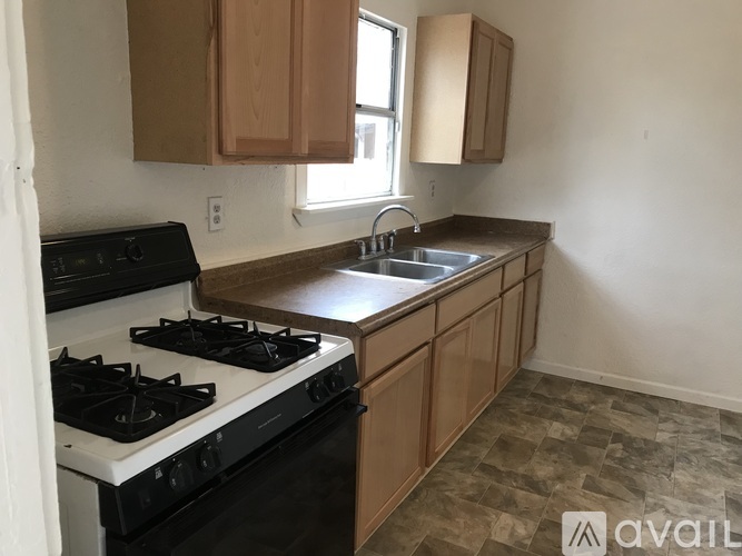 A kitchen with a black stove top oven and wooden cabinets.