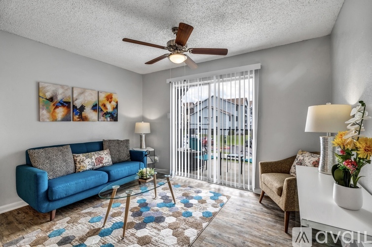 A living room with a blue couch, a rug, and a ceiling fan.