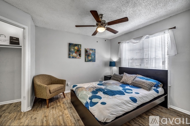 A bedroom with a bed, a chair, and a ceiling fan.