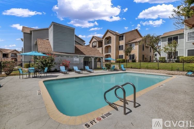 A swimming pool surrounded by a fence and chairs in front of a building.