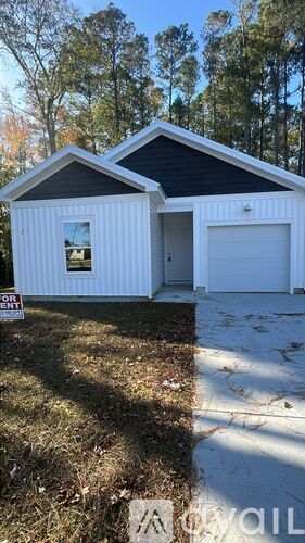 A small white house with a black roof and a garage door.