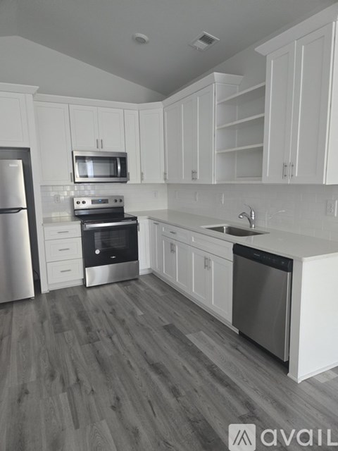 A kitchen with white cabinets and a wooden floor.