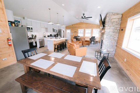 A kitchen with a table and chairs in the foreground and a stone wall in the background.