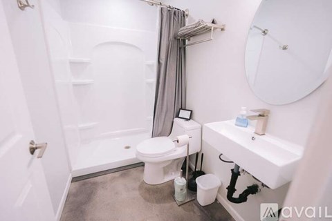 A white bathroom with a toilet, sink, and shower.