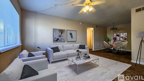 A living room with a white couch, a glass coffee table, and a ceiling fan.