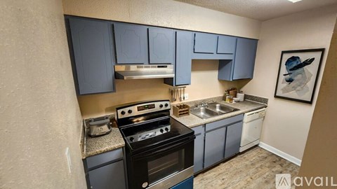 A kitchen with blue cabinets and a black stove top oven.