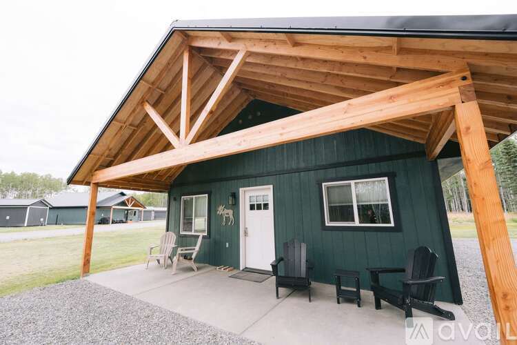 A green house with a wooden roof and a covered patio area.