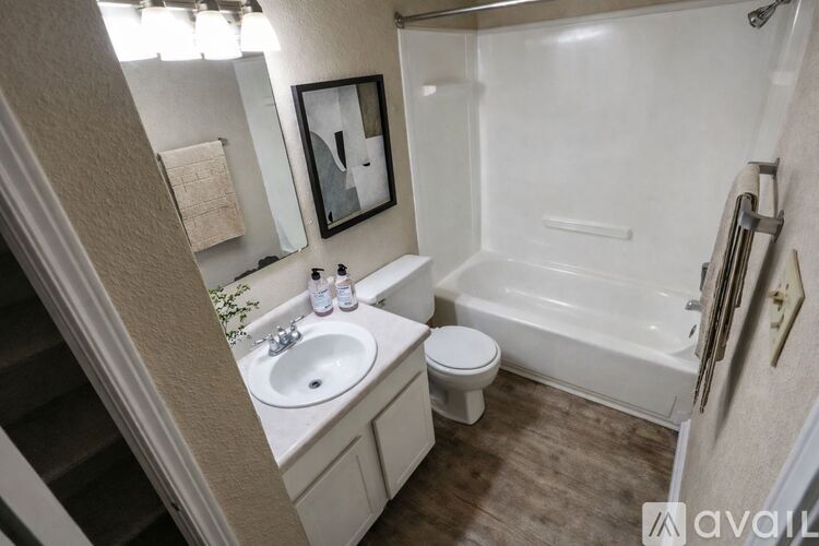 A bathroom with a white tub, sink, and toilet.