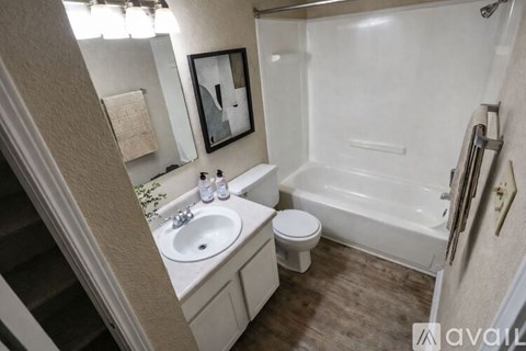A bathroom with a white tub, sink, and toilet.