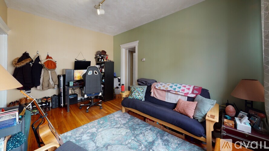 A living room with a couch, a chair, a table, a lamp, a ceiling fan, and a rug.