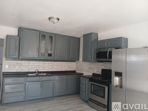 A kitchen with grey cabinets and a white fridge.