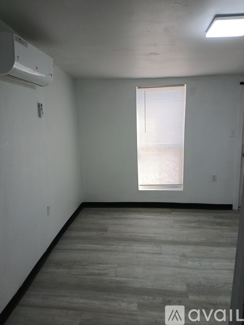 A room with a window covered by blinds and a wall-mounted air conditioner unit.