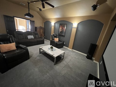A living room with a black leather couch and a white coffee table.