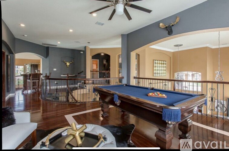 A pool table is in the middle of a room with a ceiling fan.