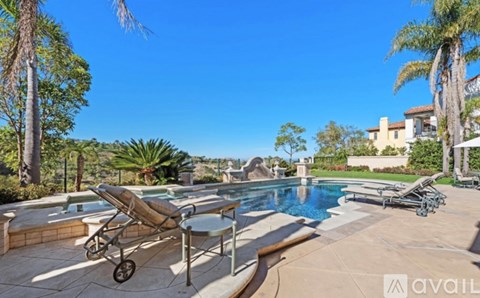 A poolside lounge chair is positioned on a patio with a pool and palm trees in the background.
