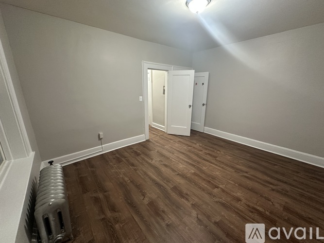 A room with wooden flooring and a radiator on the left side.