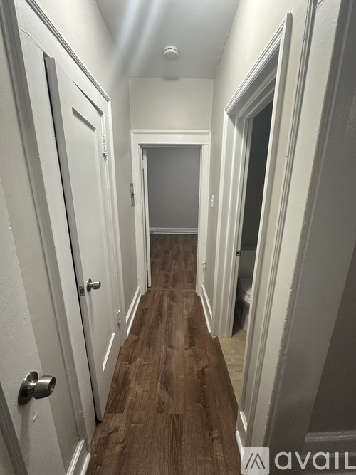 A hallway with white doors and a wooden floor.
