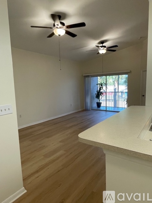 A room with a ceiling fan and a window with a view of a balcony.