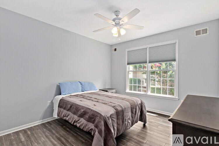 A bedroom with a bed, a ceiling fan, and a window with blinds.
