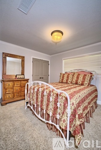 A bedroom with a bed, dresser, and mirror.