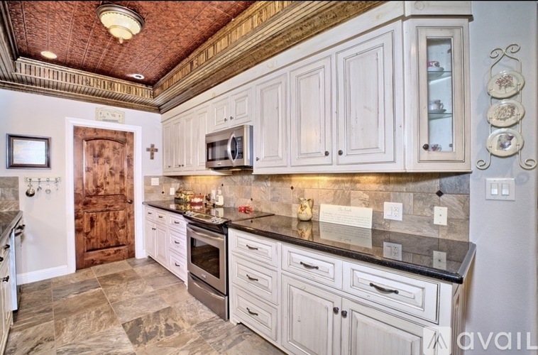 A kitchen with white cabinets and a wooden door.