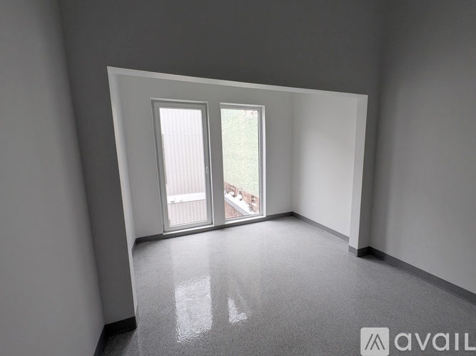 A room with a carpeted floor and a large window with a view of a balcony.